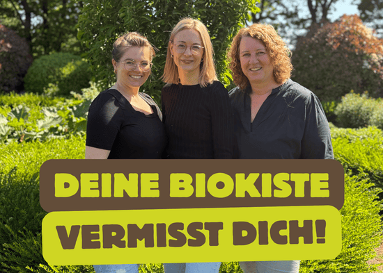 KI generiert: Ein Mann hält ein Huhn in den Armen und trägt ein T-Shirt mit dem Aufdruck "bioLesker". Im Bild steht der Text "Ihre Bio-Kiste vermisst Sie!" vor einem ländlichen Hintergrund.