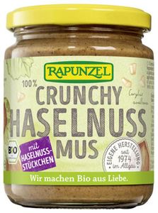 KI generiert: Das Bild zeigt ein Glas mit der Aufschrift "Crunchy Haselnussmus" der Marke Rapunzel. Es handelt sich um ein Bio-Produkt mit Haselnussstückchen.