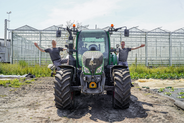 KI generiert: Ein Traktor vor Gewächshäusern, zwei Personen stehen lächelnd daneben.