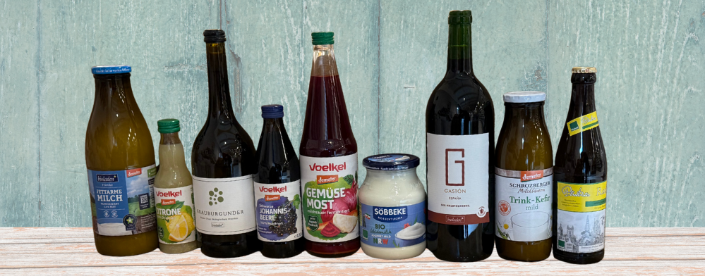 KI generiert: Eine Reihe von Getränkeflaschen und Glasbehältern stehen vor einem grünen Hintergrund. Text: „Voelkel“, „Sobbeke“.