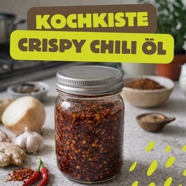 KI generiert: Ein Glas mit Crispy Chili Öl auf einer Küchenarbeitsplatte. Text: "KOCHKISTE CRISPY CHILI ÖL".