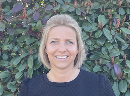 KI generiert: Eine Person lächelt vor einem grünen Busch.