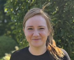 KI generiert: Eine Person lächelt im Freien mit grünem Hintergrund.