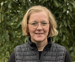 KI generiert: Eine Person mit Brille und dunkler Jacke steht vor grünem Hintergrund.