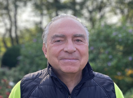 KI generiert: Ein lächelnder Mann im Freien vor unscharfem, grünem Hintergrund.